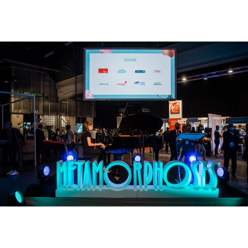 logo métamorphoses blanc brut avec des spots bleu